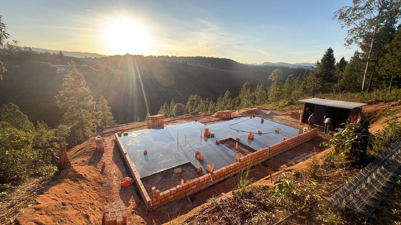 Fundação e baldrame em alvenaria de três residências em construção em condomínio fechado, com vista para a serra